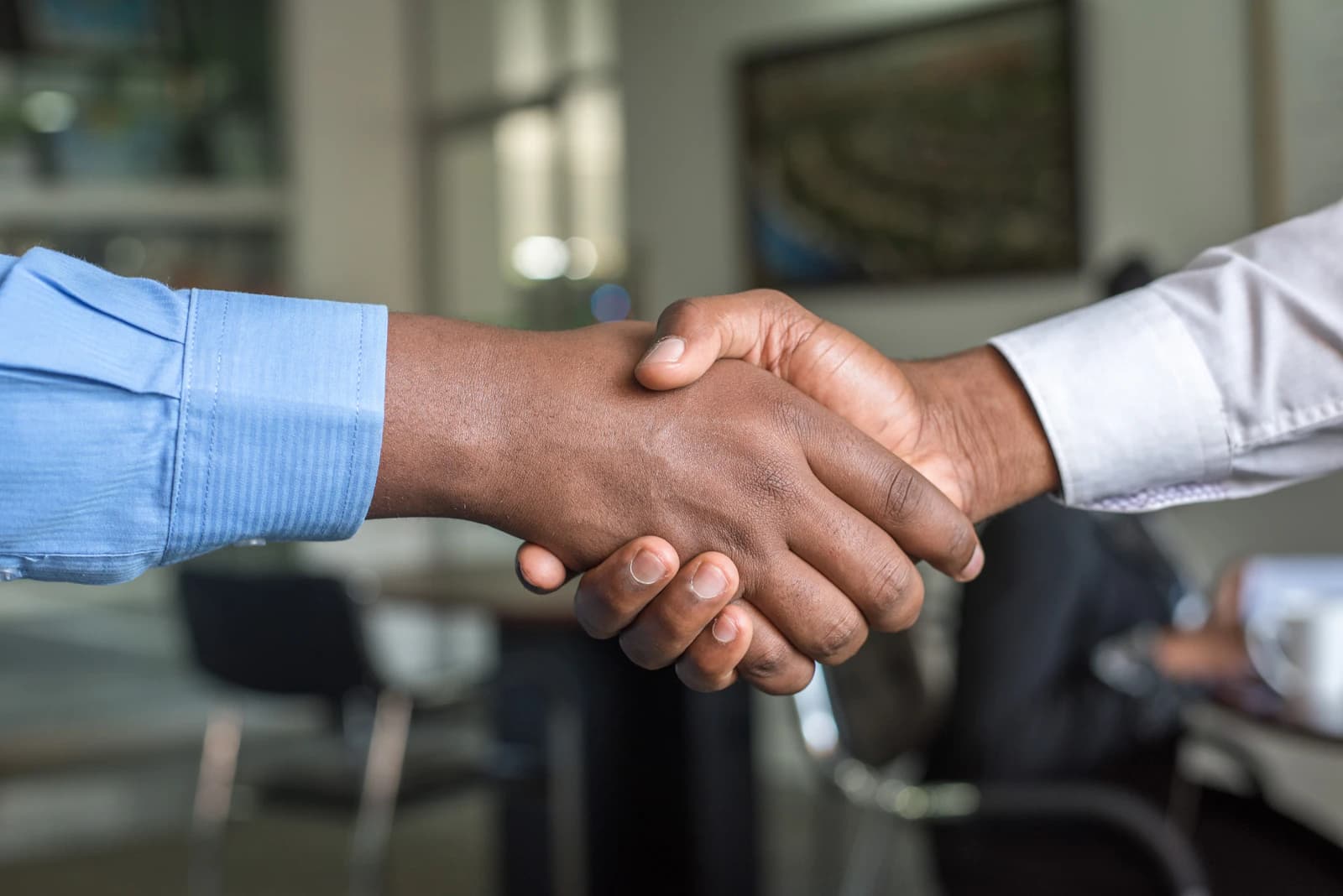 Aperto de mão entre dois executivos em ambiente corporativo selando parceria comercial